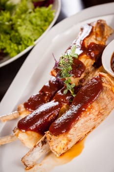 Grilled pork ribs Spareribs with barbecue sauce marinade and herb salad on a plate