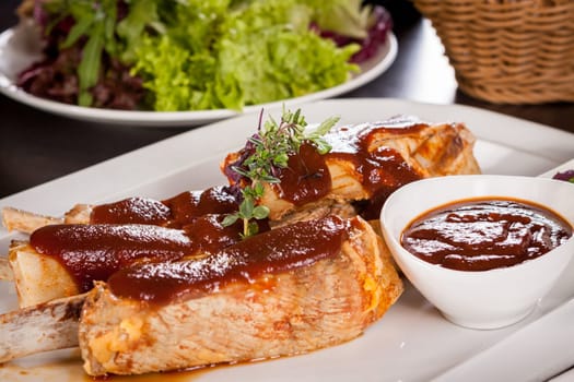 Grilled pork ribs Spareribs with barbecue sauce marinade and herb salad on a plate