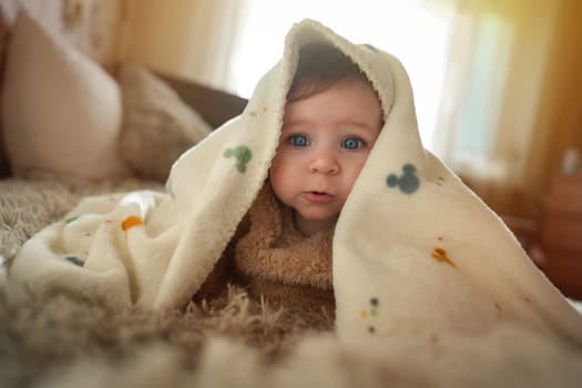 Cute baby girl crawling on bed under the blanket. Adorable kid portrait. 6 month old child. Childhood concept. High quality photo