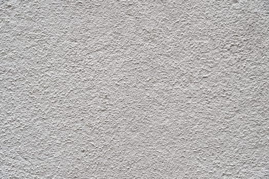 The heavy surface texture of an external wall covered in white plaster.
