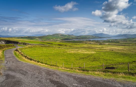 Country road leading from Kerry Cliffs to Portmagee village in a distance with view on fields and pastures, Iveragh peninsula, Ring of Kerry, Ireland