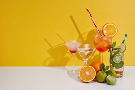 Cocktails set. Glasses with various cold colorful  beverages standing on double white yellow background with shadow. Copy space. Weekend or holiday party. Cocktail bar
