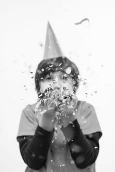 Happy kid celebrating party with blowing confetti