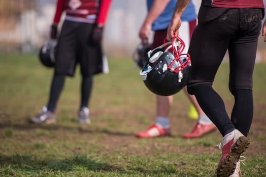 closeup shot of American football player holding black helmet at field