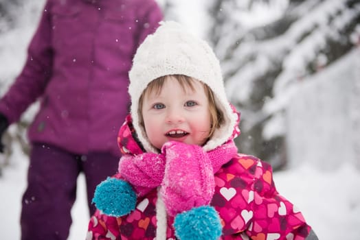 portrait of happy smiling little girl outdoors, having fun and playing on fresh snow on snowy  winter day