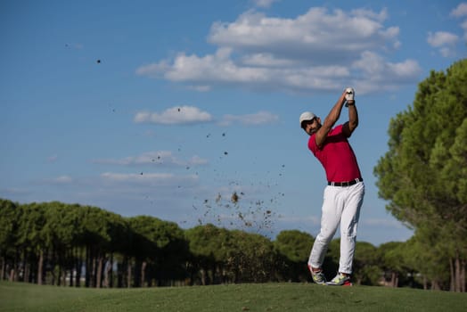 golf player hitting shot with driver on course at beautiful sunny day