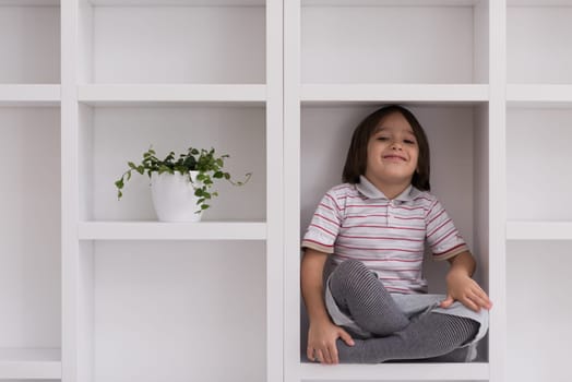 happy young boy having fun while posing on a shelf in a new modern home