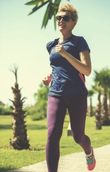 young sporty female runner training for marathon running at beautiful tropical park in the sunny morning