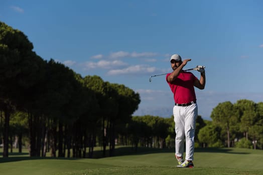 golf player hitting shot with driver on course at beautiful sunny day