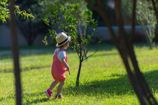 cute little girl with hat cheerfully spending time while running at Park on the summer morning