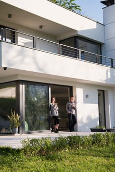 young beautiful handsome couple enjoying morning coffee on the door of their luxury home villa