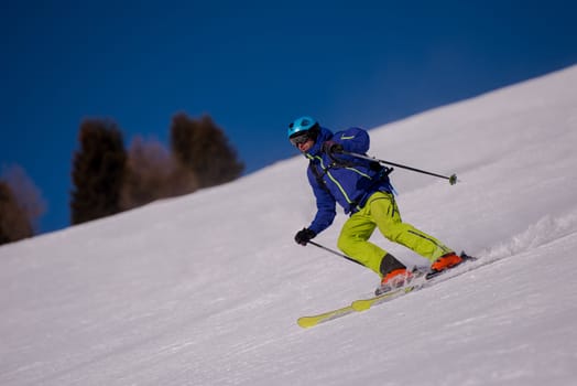 young athlete freestyle Skier having fun while running downhill in beautiful Alpine landscape on sunny day during winter season