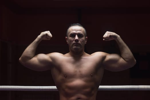 portrait of muscular professional kickboxer who standing in the ring while training for the fight