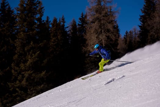 young athlete freestyle Skier having fun while running downhill in beautiful Alpine landscape on sunny day during winter season