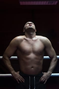 portrait of muscular professional kickboxer who standing in the ring while training for the fight