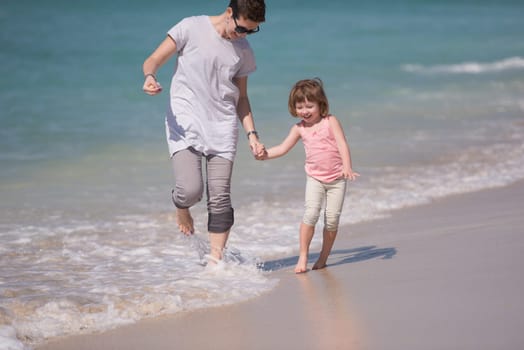 beautiful young mother and cute little girl are enjoying while running on exotic beach along the ocean Travel and Vacations.