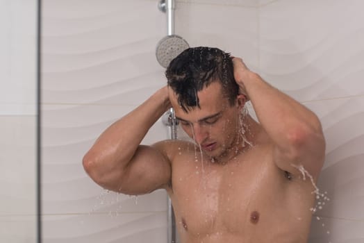 young good looking and attractive man with muscular body wet taking shower in bath