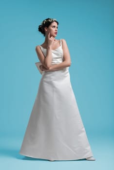 portrait of beautiful young woman as bride in wedding dress isolated on cyan backgrond in studio