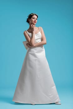 Portrait of beautiful young women in wedding dress isolated on a cyan background