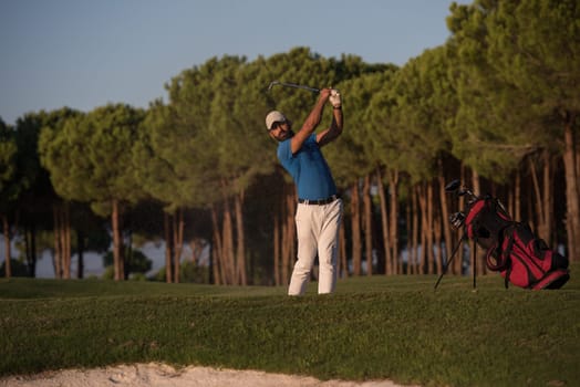 golfer shot ball from sand bunker at golf course with beautiful sunset in background