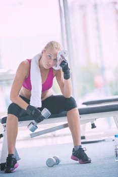 halethy young woman exercise with dumbells and relaxing on banch in fitness gym