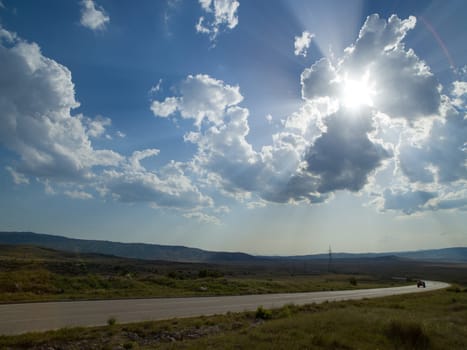 Evening summer landscape with green grass, road and clouds