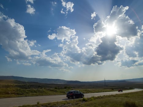 Evening summer landscape with green grass, road and clouds