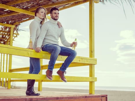 Couple Drinking Beer Together in empty beach bar during autumn time colored filter