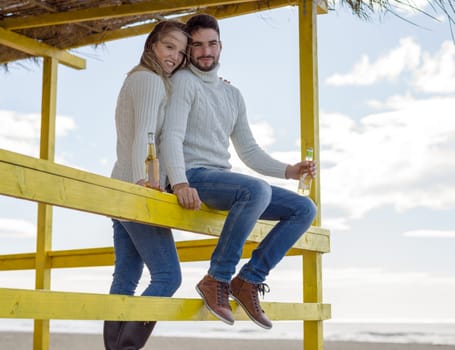 Couple Drinking Beer Together in empty beach bar during autumn time