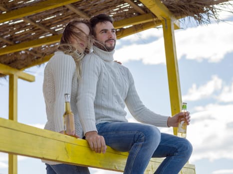 Couple Drinking Beer Together in empty beach bar during autumn time