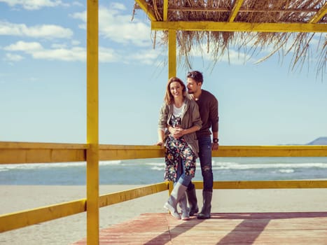 Happy couple enyojing time together on beach during autumn day colored filter
