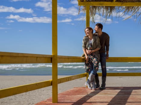 Happy couple enyojing time together on beach during autumn day