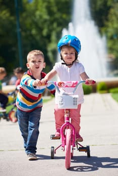Happy childrens outdoor,  brother and sister in park have fun. Boy and girl in park learning to ride a bike.