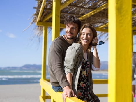 Happy couple enyojing time together on beach during autumn day