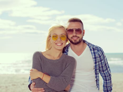 Happy couple enyojing time together on beach during autumn day colored filter