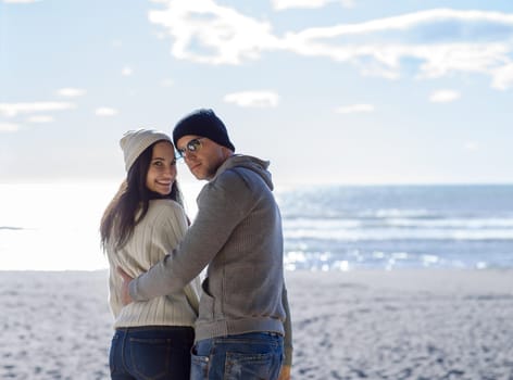 Happy couple enyojing time together on beach during autumn day