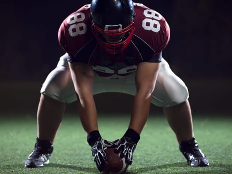 American football player starting football game on american football field at night
