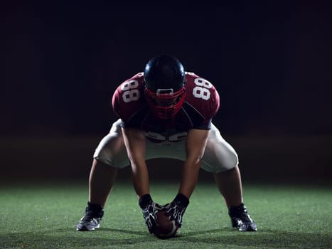 American football player starting football game on american football field at night