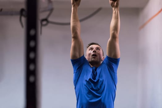 Fitness handsome man doing dipping exercise using rings in the gym