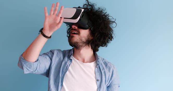 Happy man getting experience using VR headset glasses of virtual reality, isolated on blue background