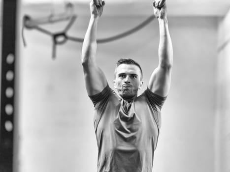 Fitness handsome man doing dipping exercise using rings in the gym