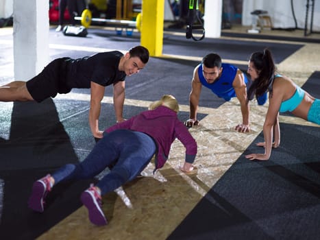 group of young healthy people doing pushups at crossfitness  gym