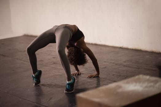 Beautiful young african american woman working out , doing yoga exercise, stretching, standing in Bridge Pose in the gym