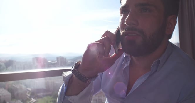 Business Man Talking On Cell Phone At Home with sun flares coming from window