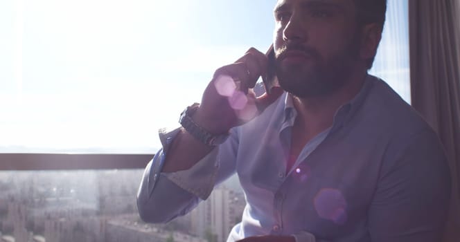 Business Man Talking On Cell Phone At Home with sun flares coming from window