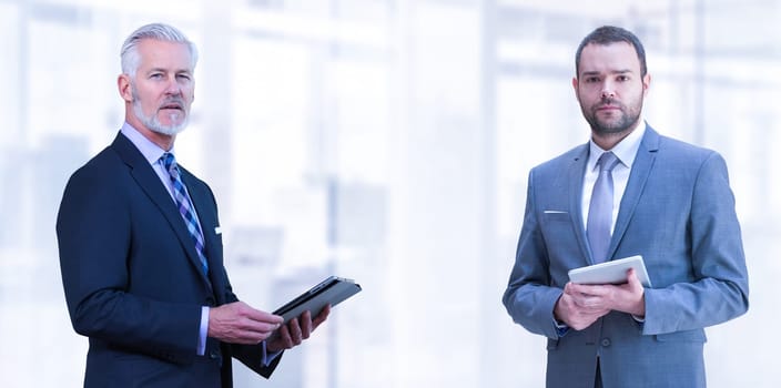 Portrait of two colleague businessmans using tablet in front of the modern IT company