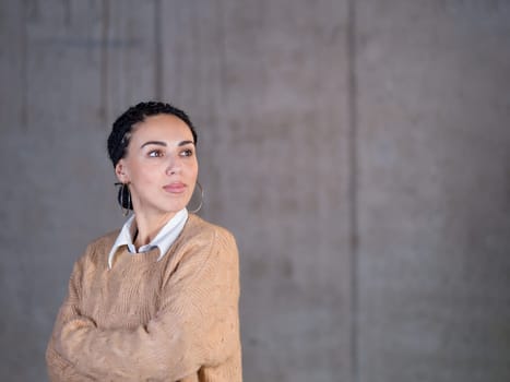 portrait of young successful smiling casual businesswoman standing in front of a concrete wall at new startup office
