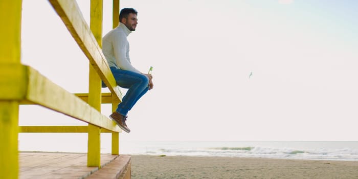 Man Drinking Beer on beach during autumn time