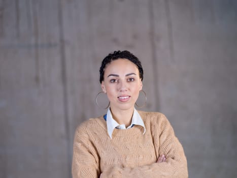 portrait of young successful smiling casual businesswoman standing in front of a concrete wall at new startup office