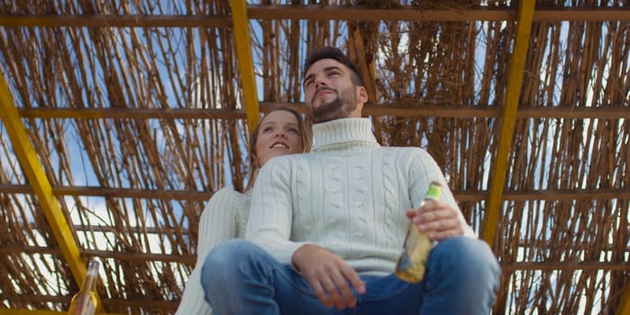 Couple Drinking Beer Together on beach during autumn time